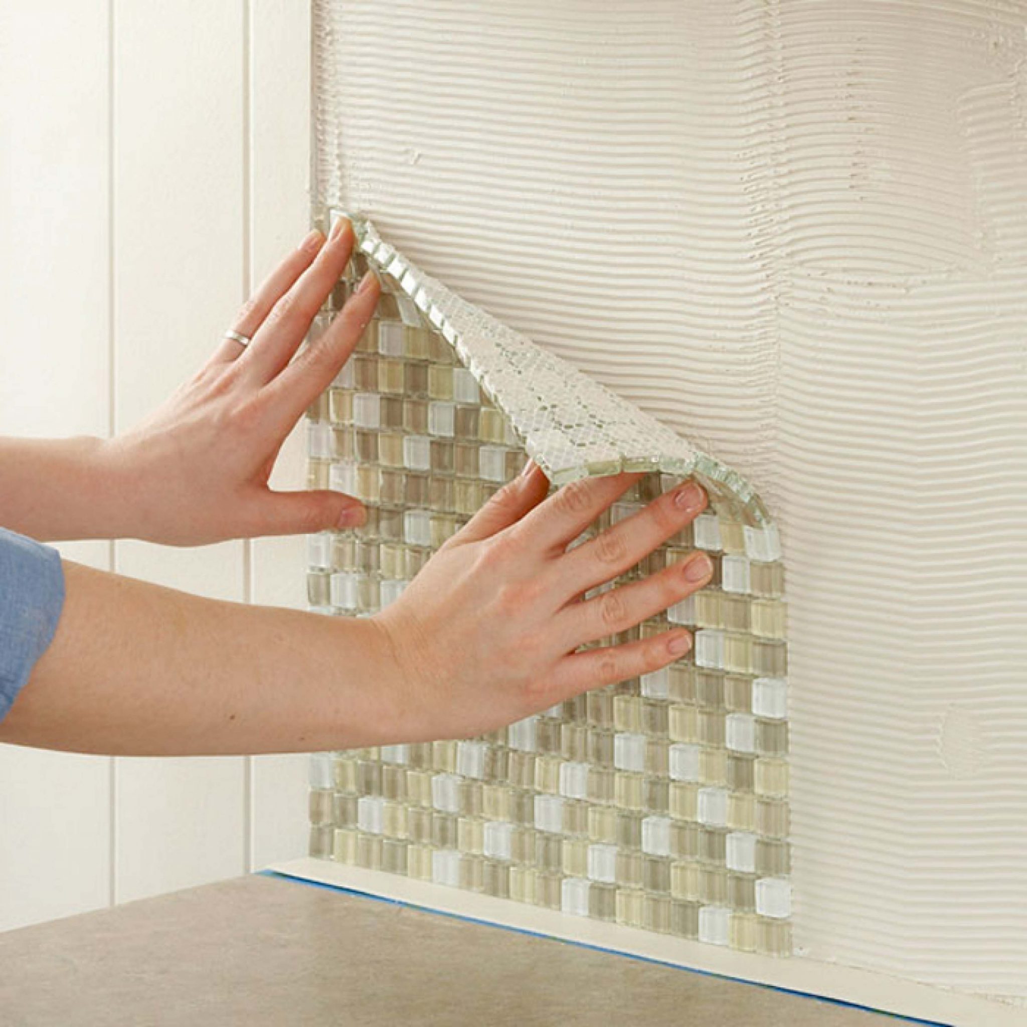 Fixing mosaic tile sheets to a wall.